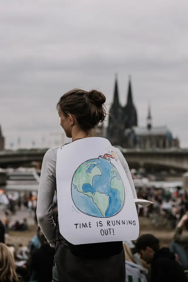 Une femme tenant une pancarte qui dit que le temps presse - Photo de Tobias Rademacher (Unsplash)